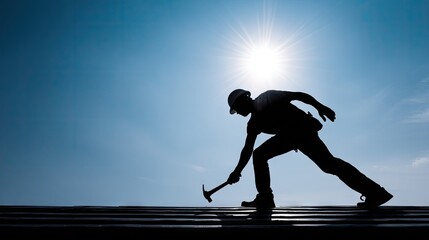 Silhouette of a construction worker hammering on a rooftop.