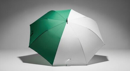 Two-tone green & white umbrella, closed, angled, studio lit with shadow