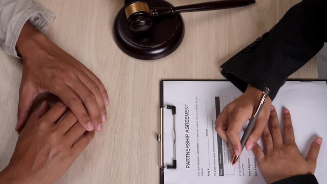 Lawyer and client shake hands after signing legal documents, symbolizing trust, agreement and legal closure.