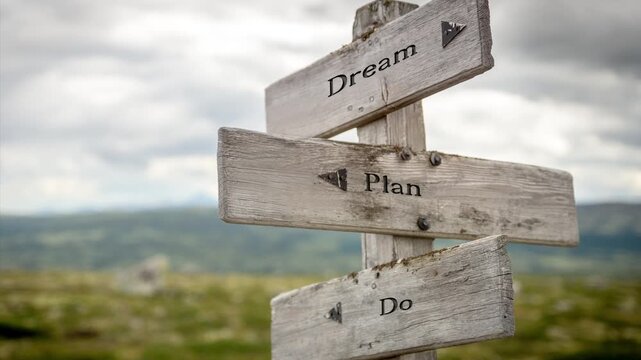 Wooden sign on a mountain plateau with the quote "Dream Plan Do", bathed in natural sunlight, inspiring motivation, creativity, and personal growth in an outdoor setting.