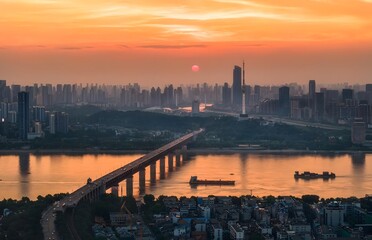 Obraz premium Wuhan China Skyline at Sunset with Bridge over Yangtze River and Golden Sky Reflection