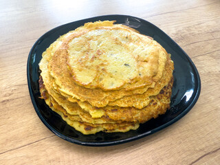 Stack of homemade potato pancakes on black plate, traditional healthy and cheap farmhouse food made from homegrown potatoes.