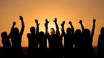 Fototapeta premium Silhouetted crowd raising arms in celebration at sunset creates inspiring teamwork and unity for success, perfect for motivation