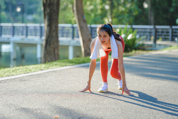 Young sportswoman preparing for running in park near lake