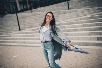 Fototapeta premium Stunning young woman with brunette hair wearing trendy casual coat and jeans enjoying her day in an urban city setting