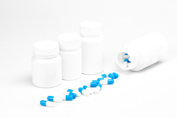 Blue and white medicine pills spilling from pharmacy bottles. Prescription drug concept. isolated on white background.
