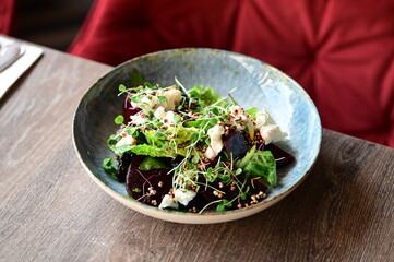 Close-up view of a fresh salad with roasted beetroot and creamy cheese, garnished with greens and herbs.