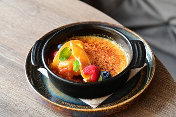 crème brûlée served with fresh fruits on a grey background.