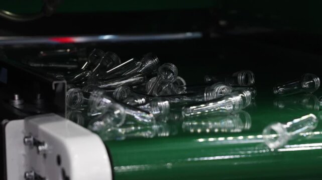 PET preforms. Making of Transparent PET plastic preforms move along automated conveyor belt in modern factory. Industrial production line concept for beverage bottles packaging automation recycling.