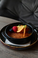 crème brûlée served with fresh fruits on a grey background.