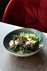 Close-up view of a fresh salad with roasted beetroot and creamy cheese, garnished with greens and herbs.