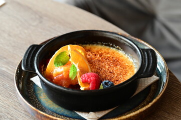 crème brûlée served with fresh fruits on a grey background.
