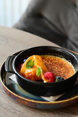 crème brûlée served with fresh fruits on a grey background.