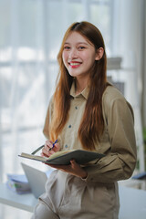 Young businesswoman smiling and taking notes in her diary at the office