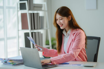 Asian businesswoman working with financial documents and using laptop in office