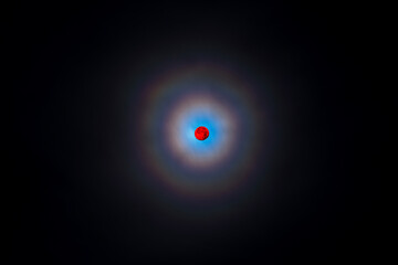 Glowing full red moon at night with double rainbow halo, ring of light