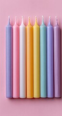 Row of pastel-colored birthday candles on a pink background