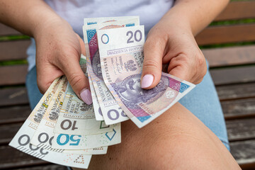 Female hands holding and counting PLN banknotes, Polish zloty currency money closeup