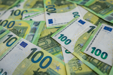 Obraz premium Stack of 100 euro banknotes scattered in close-up view symbolizing wealth and finance