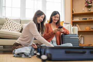 Young asian woman and friend preparing luggage packing clothes in suitcases for travel at home, planning holiday travel, content creator and travel blogger, friendship moments lifestyle vacation trip