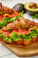 Delicious croissant sandwiches with smoked salmon, avocado, and lettuce filling