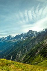 Obraz premium A mountain range with snowy peaks and grassy hills in front