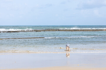 Woman bending down at the shore in playful pose on a sunny beach.
