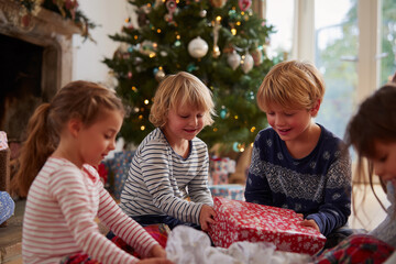 children opening gifts with excitement, wrapping paper everywhere, real family moment, festive