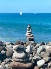 Stone Cairns on Rocky Beach with Blue Sea in Background