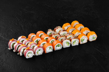 Delicious sushi rolls set displayed on black background