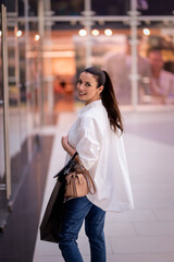 Fototapeta premium Smiling brunette haired woman walking in a shopping mall