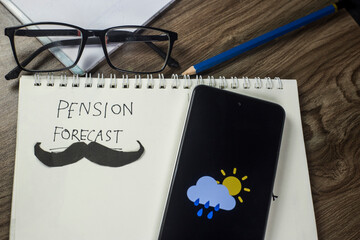 Pension forecast concept, weather sign on mobile screen, written text on notepaper on wooden...