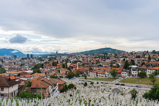 top panoramic view of muslim religious cementery in sarajevo city with huge areas and neighbourhoods of houses in cloudy day with mountains around bosnia