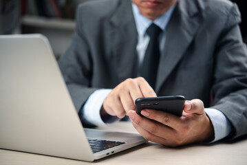 businessman uses a smartphone, laptop computer at an office desk to manage online communication, schedule meetings, and boost productivity. concept mobile digital workflow.
