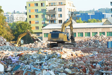 Demolition of an old apartment building with a yellow excavator in the foreground