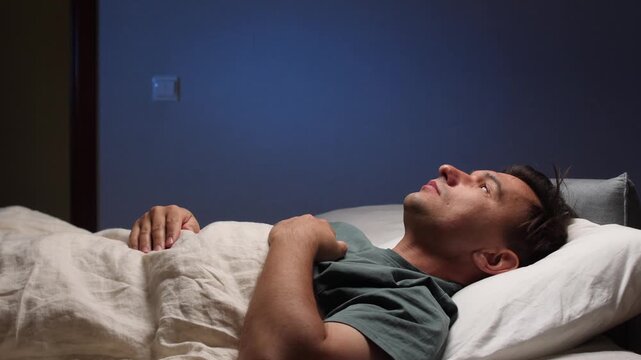 Sleepy man yawning in bed at night
