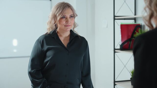 real estate agent rises to present key as client stretches forth hand to receive key and they exchange handshake with warm demeanor beside pen holder on office table