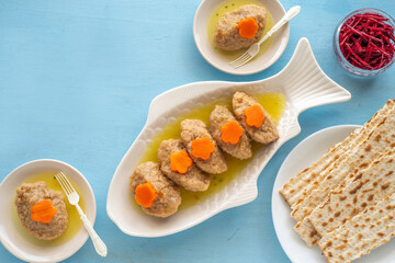Gefilte fish served with carrots on traditional platter over blue wooden background. Food for Jewish holiday Pesach or Passover.
