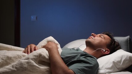 Man relaxing in bed listening to music with earphones