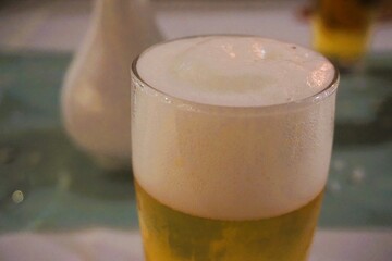 Frisch gezapftes Bier in Glas steht auf festlich gedecktem Risch auf Feier in Restaurant am Abend 