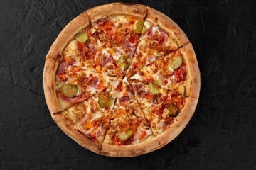 Sliced pizza with various toppings on a black background is waiting to be enjoyed