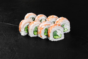 Sushi rolls covered with salmon and filled with cucumber, avocado and cream cheese resting on dark background