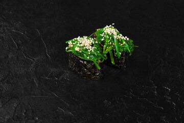 Gunkan maki sushi with chuka seaweed and sesame seeds on black background © nazarovsergey