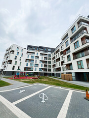 Modern apartment building with outdoor playground and parking spaces in residential complex