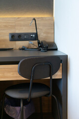 Contemporary desk with black chair and power outlets in a hotel room, designed as a workspace for business travel, office, or home use.