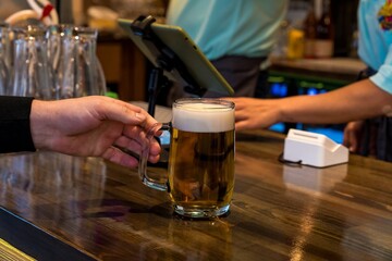 Hand Taking a Glass of Beer at Bar Counter