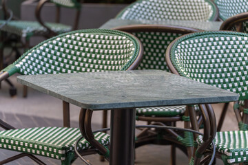 Empty green and white cafe chairs and a marble table await guests. The scene appears calm and inviting.
