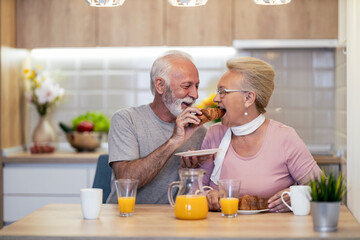 Couple enjoys breakfast together in a cozy kitchen, sharing moments of joy and laughter with pastries and juice