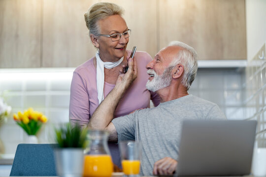 Elderly couple enjoying quality time together in a modern kitchen while sharing a light-hearted moment - Powered by Adobe