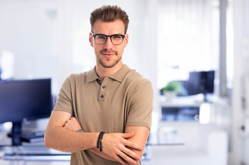 Fototapeta premium Confident young man standing at the office and looking at camera